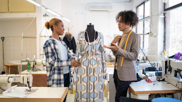 Rainbow fashion students professional fashion designer, discussing patterns and ideas of new couture collection with a female tailor in his studio. Dressmaking, creativity and tailoring concept.