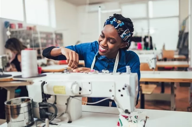 rainbow fashion design student operating industrial machine